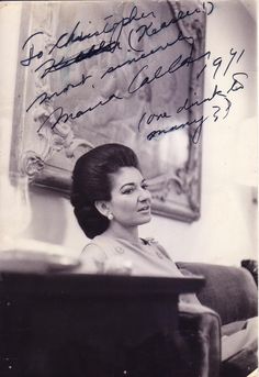 an old black and white photo of a woman sitting in a chair with writing on the wall behind her