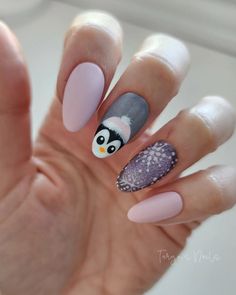 This adorable winter gel nail design captures the playful spirit of the season with a cute penguin accent on one nail, paired with a soft pastel palette. The design features a short almond shape, making it practical yet eye-catching. The use of matte light pink polish on two nails adds a neutral and simple base, while the penguin and snowflake art on the remaining nails add a playful, wintery flair. The subtle glitter on the snowflake nail gives the whole design a classy sparkle without being too flashy. Penguin Nail Designs, Polar Bear Nails, Light Pink Polish, Simple Gel Nail Designs, Penguin Nail Art, Short Almond Shape, Penguin Nails, Snowflake Art, Winter Nails Gel