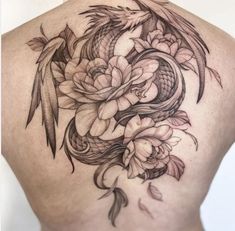 the back of a woman's body with flowers and fish tattoos on her stomach