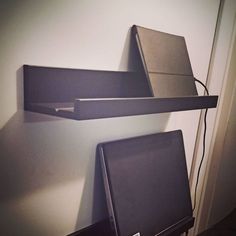 two electronic devices sitting on top of each other in front of a wall mounted shelf