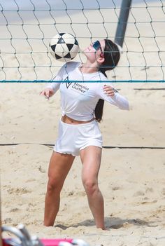 a woman hitting a volleyball on the beach