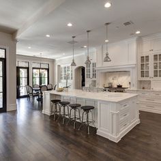 a large kitchen with white cabinets and wooden floors