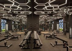 an empty gym with rows of exercise machines and lights hanging from the ceiling above them