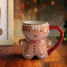 a coffee mug with a ginger face on it sitting next to a framed photo and christmas tree