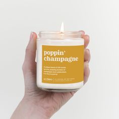 a hand holding a candle that says poppin'champagne on the front and bottom