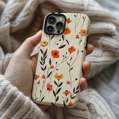 a person holding an iphone case with flowers on it in front of a white blanket