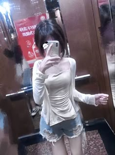 a woman standing in front of a mirror taking a selfie with her cell phone