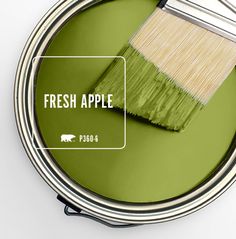 a green paint can with a brush in it and the words fresh apple on top