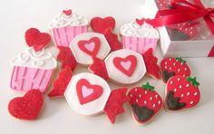 some decorated cookies with hearts and cupcakes on them next to a gift box