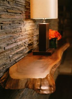 a wooden table with a candle on it next to a brick wall and flowers in vases