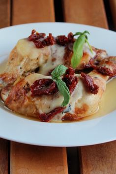 a white plate topped with ravioli covered in sauce and garnished with green leaves