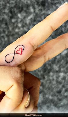 a person's finger with a heart tattoo on it