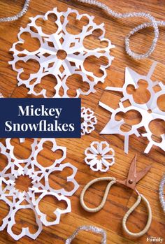 some snowflakes are sitting on a table with scissors and string attached to them