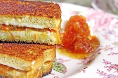 two grilled cheese sandwiches sitting on top of a flowered plate next to jelly