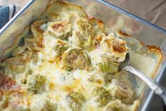 a casserole with broccoli and cheese in a glass dish on a wooden table