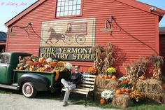 an old truck is parked in front of the vermont country store with pumpkins and gourds