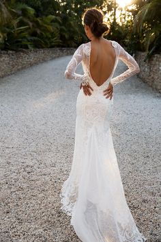 a woman in a long white dress is standing on the ground with her back to the camera