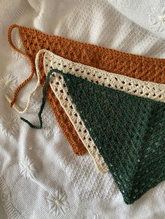 three crocheted placemats sitting on top of a white table cloth covered in green and brown yarn