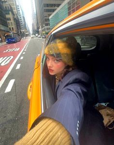 a woman sitting in the driver's seat of a taxi cab on a city street