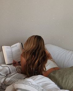 a woman laying in bed reading a book