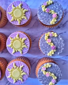 cupcakes decorated with frosting and decorations on a marble counter top, arranged in the shape of sunflowers