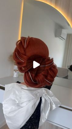 the back of a woman's head with red hair in a bun and pearls on it