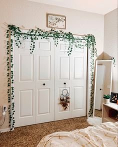 a bedroom with white doors and ivy on the wall