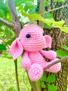 a pink crocheted stuffed animal sitting on top of a tree branch