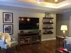 a living room filled with furniture and a flat screen tv mounted on the wall above it