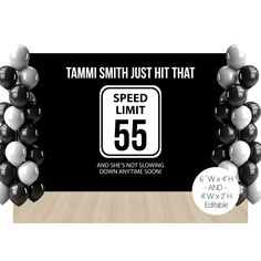 a speed limit sign surrounded by black and white balloons in front of a wood floor