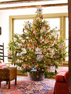 a decorated christmas tree in a living room with pictures on the branches and ornaments around it