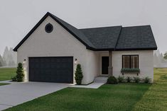 a white house with black roof and two garages