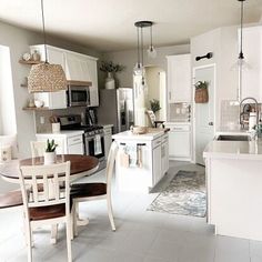 a kitchen filled with lots of white furniture and decor on top of tile flooring