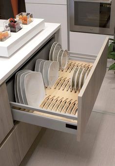 an open drawer in a kitchen filled with plates and silverware next to a counter