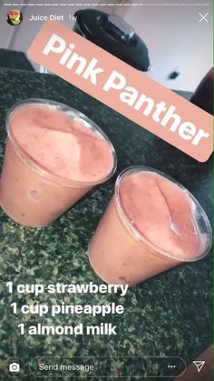 two cups filled with pink drink sitting on top of a counter next to each other