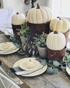 the table is set with white pumpkins and greenery