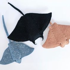 three different types of hats on a white surface, one has a cat's head and the other has a fish's tail