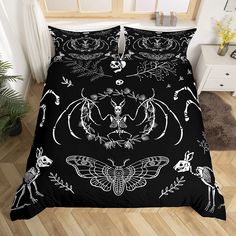 a bed with black and white designs on the comforter, next to a potted plant