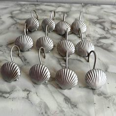 twelve silver seashell hooks on marble counter top