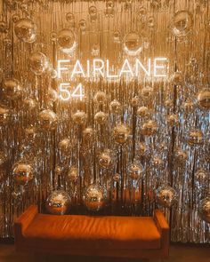 an orange couch sitting in front of a wall covered with shiny balls