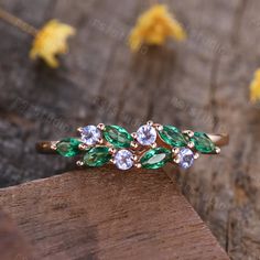 a close up of a ring on a wooden surface with flowers in the back ground