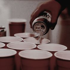 a person pours soda into cups on a table with other cups in the background