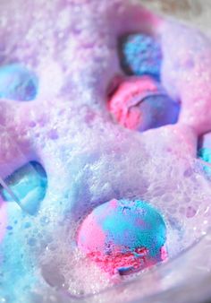 the bathtub is filled with soapy bubbles and blue, pink, and purple balls