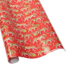 a red wrapping paper with leopards and flowers printed on the side, rolled up