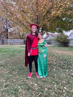 two people dressed up in costumes standing next to each other on a grass covered field