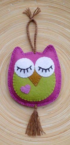 an owl ornament is hanging on a tree branch with a tassel in the shape of a heart