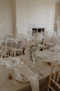 the tables are set with white flowers in vases and place settings for dinner guests