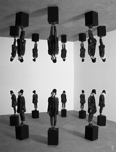 black and white photograph of people standing in front of multiple cubes on pedestals