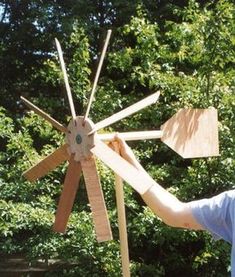 a man is holding up some wooden windmills