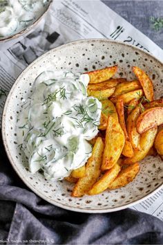 a bowl filled with potato wedges covered in sour cream and garnished with dill